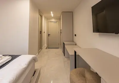 a corridor of a hotel room with a bed and a tv at Safir Termal & Spa Otel in Çekirge İstasyonu