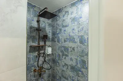 a bathroom with a shower with blue tiles at Safir Termal & Spa Otel in Çekirge İstasyonu