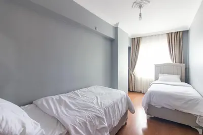 a white bedroom with two beds and a window at Spacious & Modern 3BR Apartment Central Şişli in Istanbul
