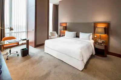 a hotel room with a large white bed and a desk at Sheraton Grand Istanbul Atasehir in Istanbul