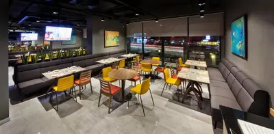 a restaurant with tables and yellow chairs and a bar at Fraser Place Antasya Istanbul in Istanbul