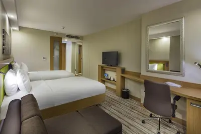 a hotel room with a bed and a desk and a mirror at Hampton by Hilton Istanbul Atakoy in Istanbul