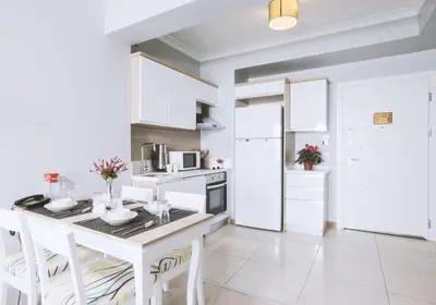 a white kitchen with a white table and chairs at Serenity Suites Istanbul Airport in Istanbul