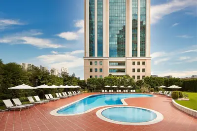 a swimming pool with chairs and a tall building at Istanbul Marriott Hotel Asia in Istanbul