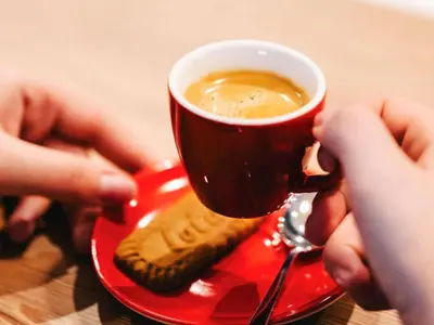 a person holding a cup of coffee and a cookie at Ibis Istanbul West in Istanbul