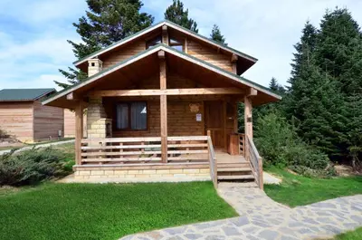 a log cabin with a porch and green grass at Uludag Orman Koskleri in Uludag