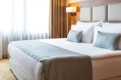 a bedroom with a large white bed with blue pillows at Clarion Hotel Istanbul Mahmutbey in Istanbul