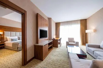 a hotel room with a couch and a bed and a television at Clarion Hotel Istanbul Mahmutbey in Istanbul