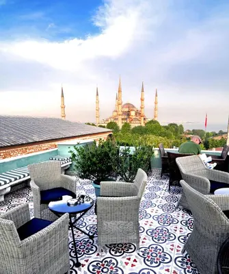 a patio with chairs and tables with a view of the mosque at Hotel Ibrahim Pasha in Istanbul