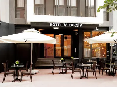 a restaurant with tables and umbrellas in front of a building at Taksim Hotel V Plus in Istanbul