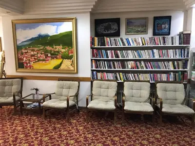 a library with three chairs and bookshelves filled with books at Hotel Cesmeli in Bursa