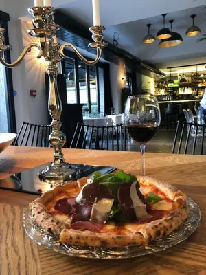 a pizza on a table next to a glass of wine at Nabu Hotel Karaköy in Istanbul