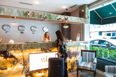 a woman standing behind a counter with a suitcase at Boutique Princess Hotel in Istanbul