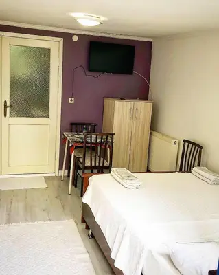 a room with two beds and a table and a tv at Ozdemir Pansiyon in Heybeliada
