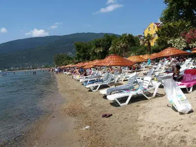 a group of chairs and umbrellas on a beach at Sağlık Apart Pansiyon in Erdek