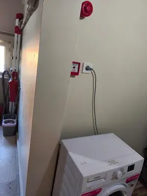 a room with a white wall and a microwave at Sağlık Apart Pansiyon in Erdek