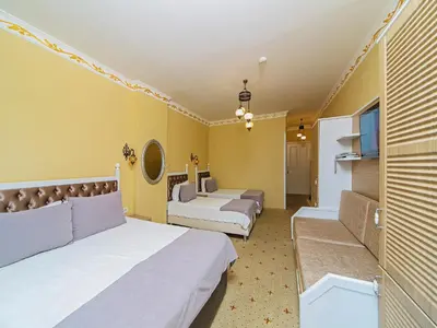 a room with three beds with yellow walls at Modern Sultan Hotel in Istanbul