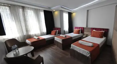 a hotel room with three beds and a table and a chair at Waha Hotel in Bursa