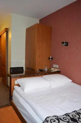 a bedroom with a large white bed with a wooden headboard at Atlas Otel in Bursa