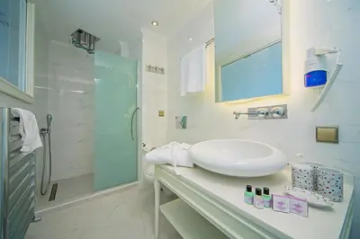 a white bathroom with a sink and a shower at Ada Hotel Istanbul in Istanbul