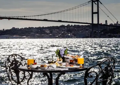 a table with food on it next to the water with a bridge at Bosphorus Palace Hotel in Istanbul