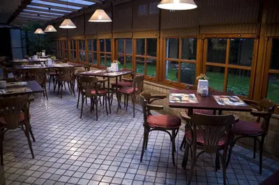 a restaurant with wooden tables and chairs and windows at Güneş Hotel Merter in Istanbul
