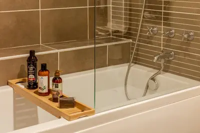 a bath tub with a shower and bottles of alcohol at Parkhouse Hotel & Spa in Istanbul