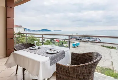 a table and chairs on a balcony with a view of the ocean at Buyukada Comfort OTEL in Buyukada