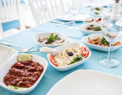 a table with bowls of food and glasses of wine at Buyukada Comfort OTEL in Buyukada