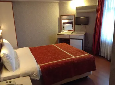 a hotel room with a bed and a desk with a mirror at Tayhan Hotel in Istanbul