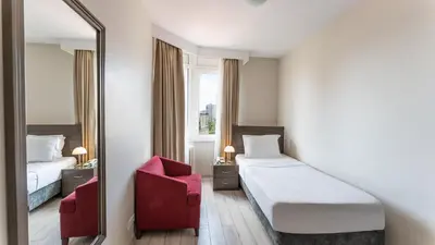 a hotel room with a bed and a red chair at The Marmara Suadiye Residence in Istanbul