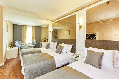 a hotel room with three beds and a table and chairs at Seres Hotel Old City in Istanbul