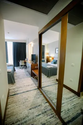 a hotel room with a bedroom and a mirror at Baia Bursa Hotel in Bursa