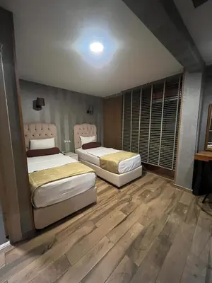 two beds in a room with wooden floors at Kuzen Otel in Istanbul