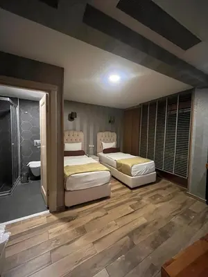 a bedroom with two beds and a bathroom at Kuzen Otel in Istanbul