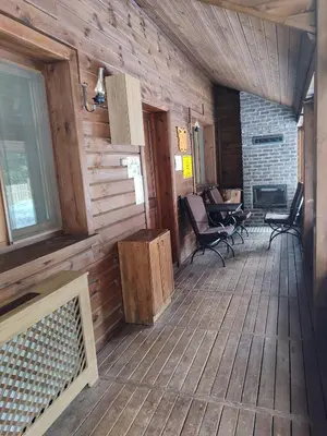 a porch of a wooden cabin with chairs and a fireplace at Karinna Orman Evleri in Uludag