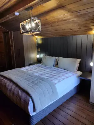 a bedroom with a large bed with a wooden wall at Karinna Orman Evleri in Uludag