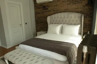 a bedroom with a white bed and a brick wall at Louis Rooms in Istanbul