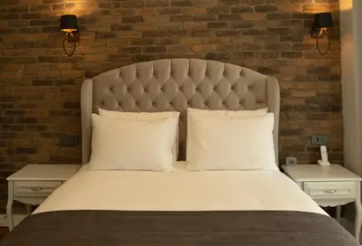 a bedroom with a large bed with a brick wall at Louis Rooms in Istanbul