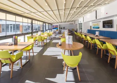 a cafeteria with wooden tables and yellow chairs at Hampton by Hilton Istanbul Kurtkoy in Istanbul