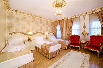 a bedroom with two beds and two red chairs at White House Hotel Istanbul in Istanbul