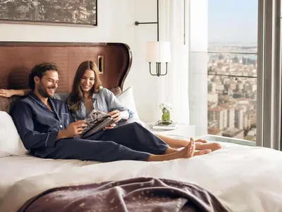 a man and a woman sitting on a bed at Fairmont Quasar Istanbul Hotel in Istanbul