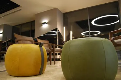 two yellow and green ottomans in a room with chairs at The City Suites in Istanbul