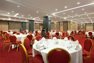 a banquet hall with white tables and red chairs at Ramada Encore by Wyndham Gebze in Gebze