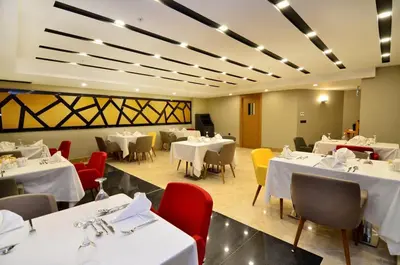a dining room with white tables and red chairs at Ramada Encore by Wyndham Gebze in Gebze