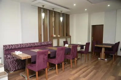 a dining room with a table and purple chairs at Hande Hotel in Mustafakemalpaşa