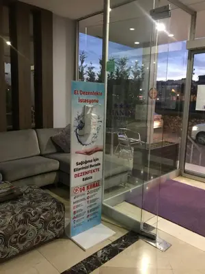 a sign in a room with a couch and a window at Hande Hotel in Mustafakemalpaşa