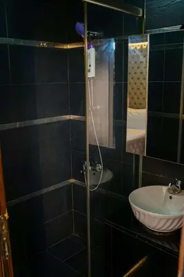 a black tiled bathroom with a sink and a mirror at Ömer Agah Istanbul Hotel Bayrampasa in Istanbul