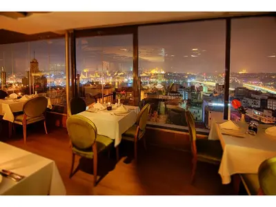 a restaurant with tables and chairs and a view of a city at Anemon Koleksiyon Galata Otel in Istanbul