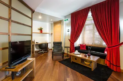 a living room with a television and red curtains at Taxim Suites Residences Istanbul in Istanbul